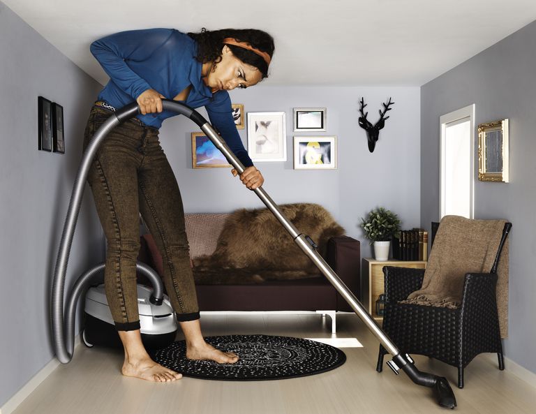 หญิง vacuum cleaning in smallscale living room