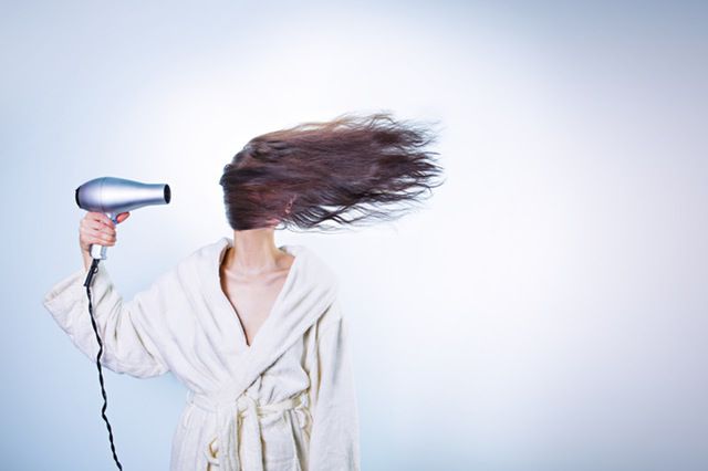Kvinna blow drying hair