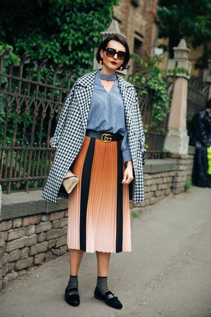 महिला wearing a gingham coat and top with a pleated skirt in orange and black