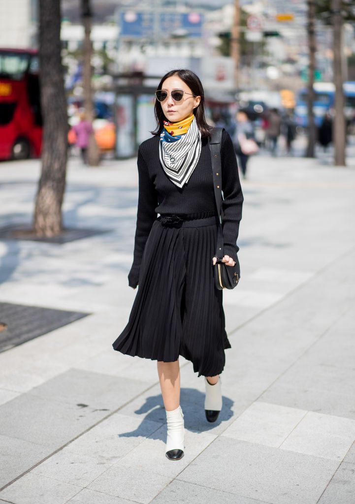 אִשָׁה wearing black top and black pleated maxi skirt with colorful silk scarf