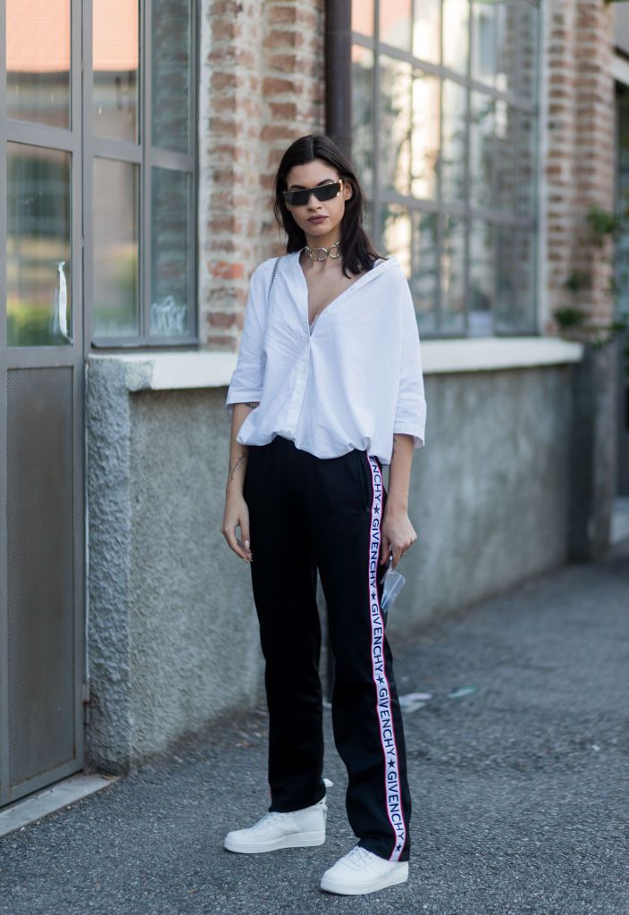 Kvinna in white shirt and striped track pants