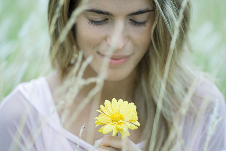 אִשָׁה with blond hair looking at flower