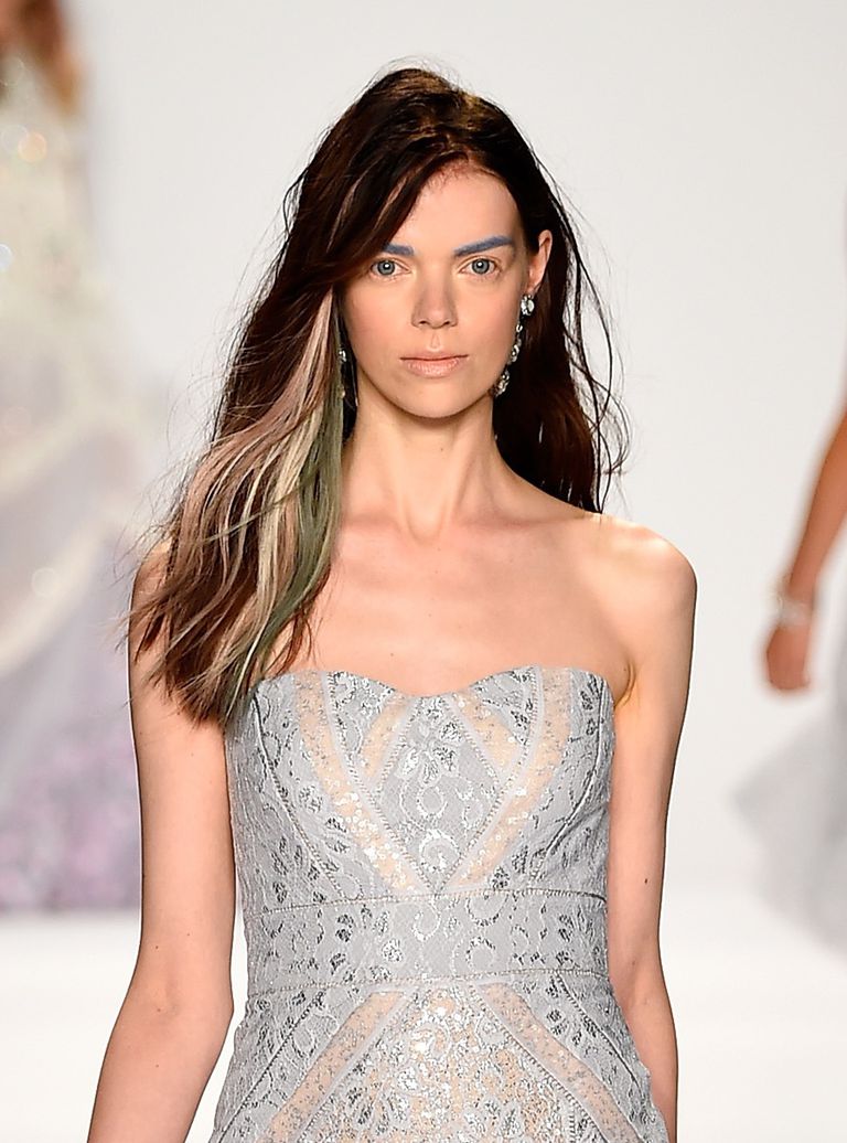 א model walks the catwalk in strands of multi-colored hair