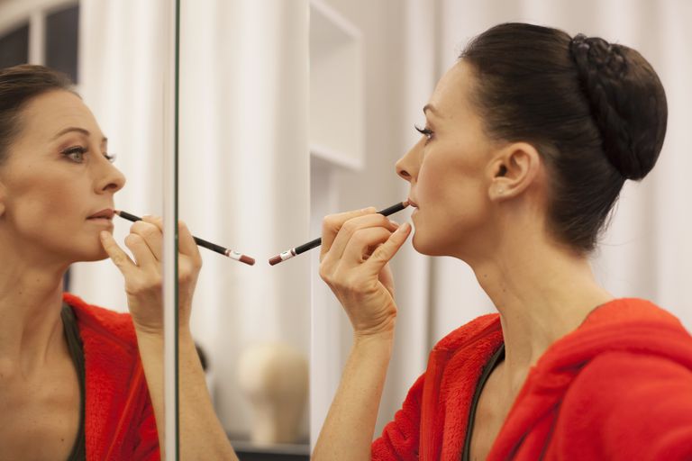 महिलाओं applying lipstick