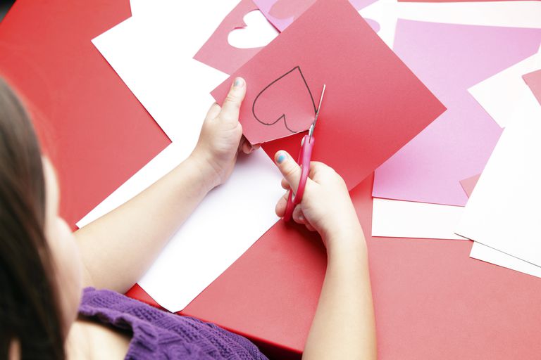 Flicka cutting out Valentine's Day hearts