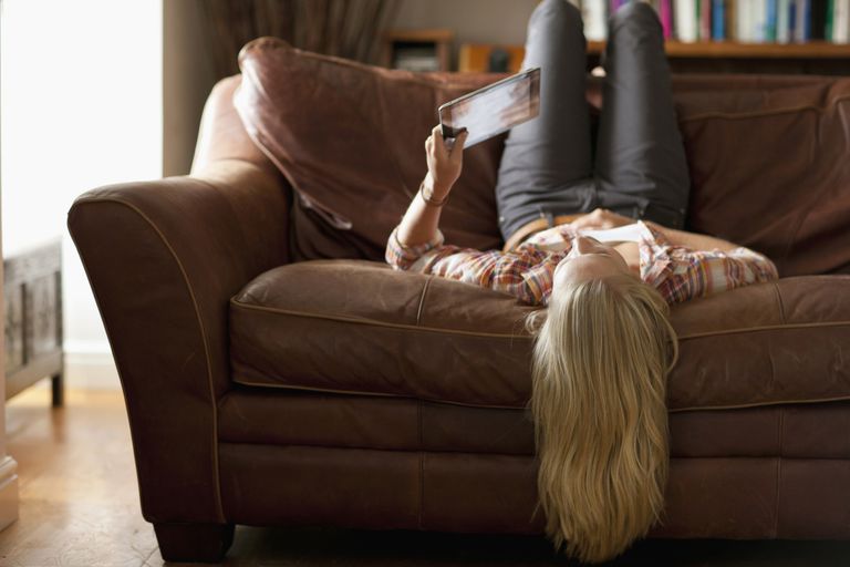 Ženska laying upside down on sofa.