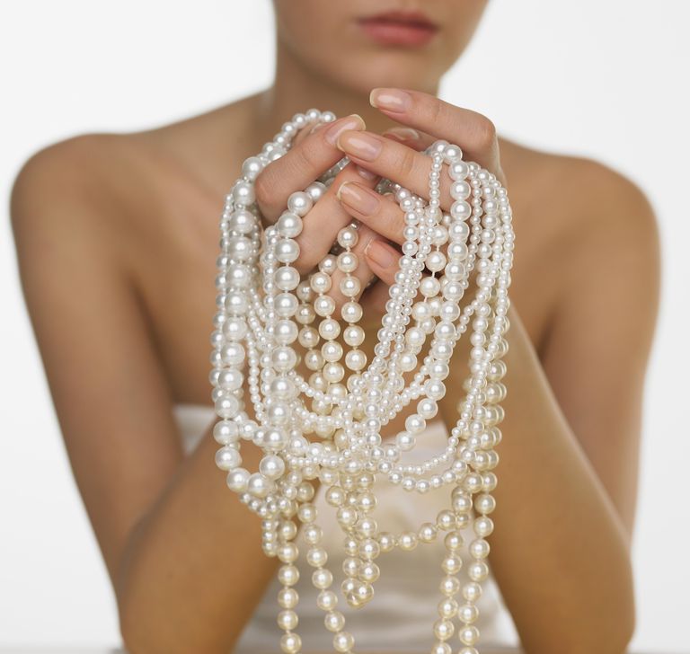 महिला holding pearls, mid section, close-up
