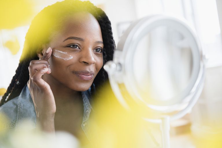 Negru woman moisturizing her face