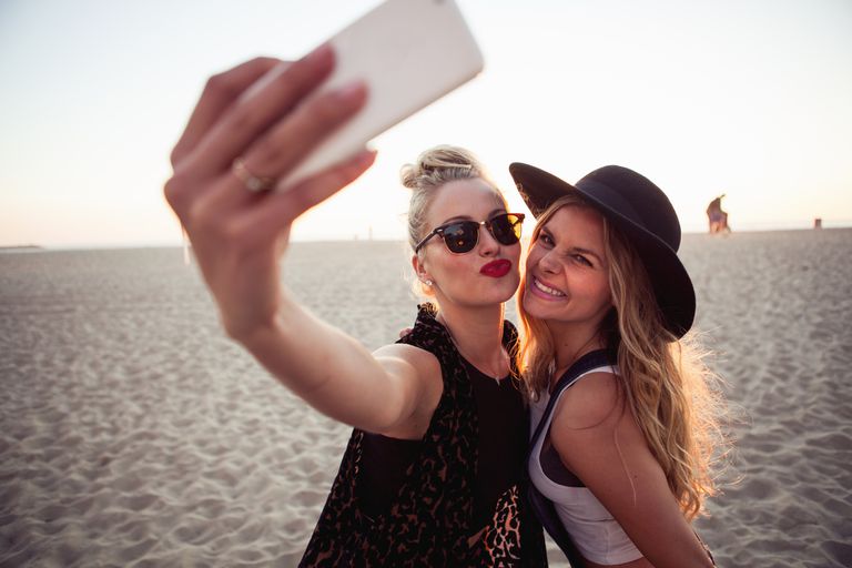 נשים taking selfies on the beach.