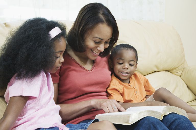 anne with children (4-7) on sofa, reading bible, smiling