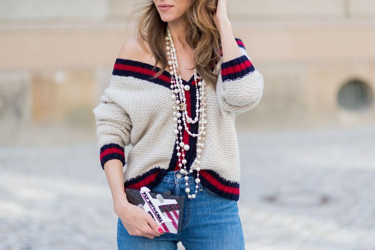 אִשָׁה wearing multiple pearl necklaces and a sweater and jeans