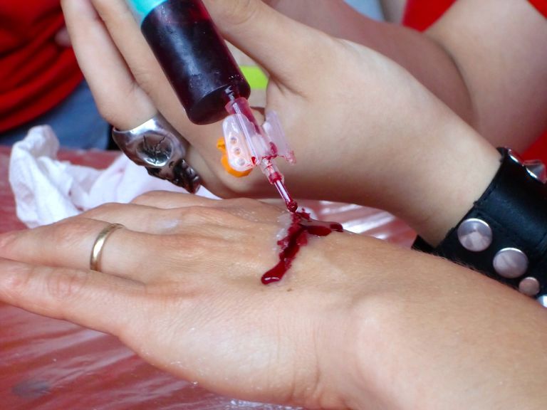 א woman applying fake blood as part of makeup.