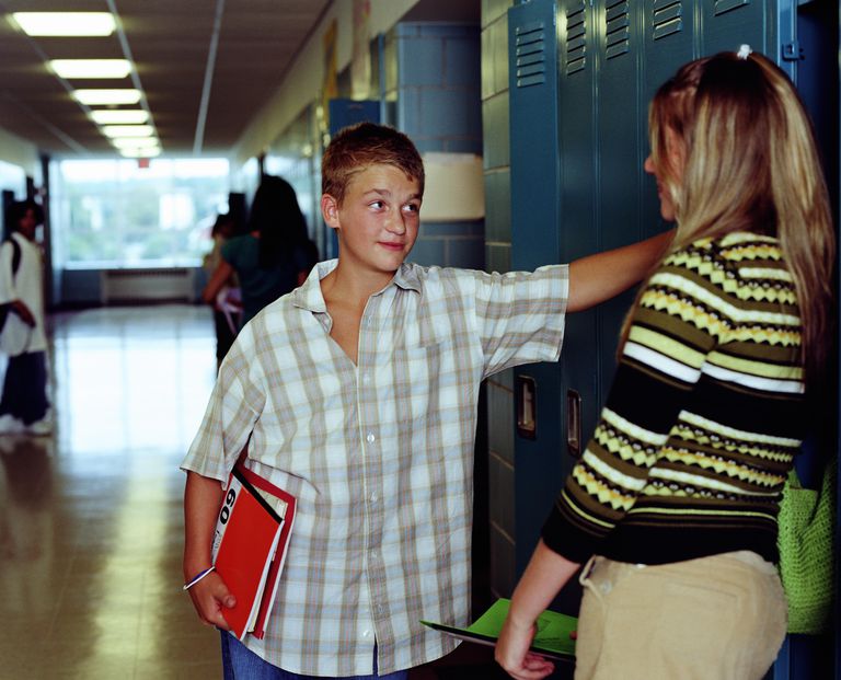 Tonåringar (13-15) talking in high school hallway, near lockers