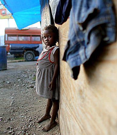 Ан orphan stands by a Haiti orphanage, which is currently housed in tents in a tent city in Haiti.