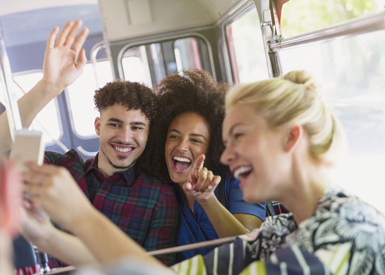 Entusiastisk friends taking selfie on bus