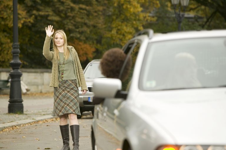 теен girl waving goodbye to friend driving away