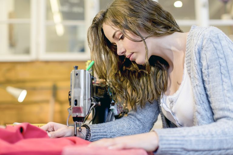 א young seamstress works behind her sewing machine.
