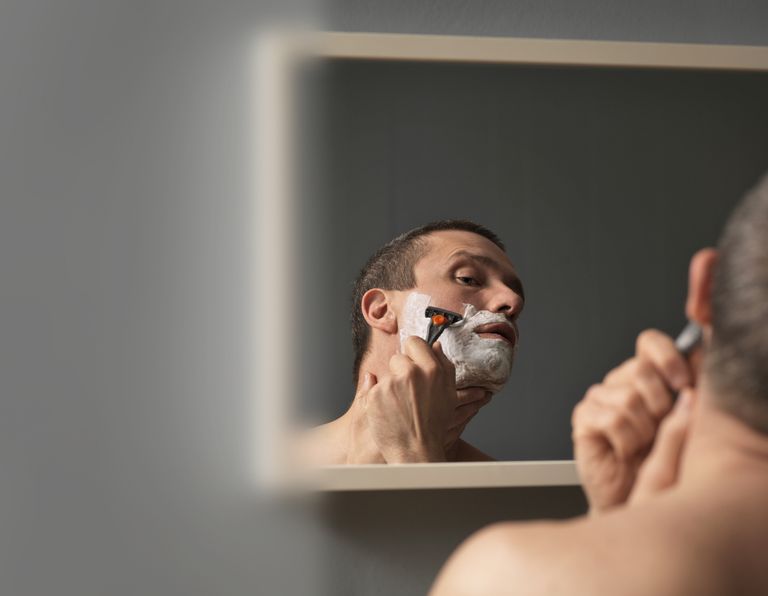 आदमी shaving face with razor