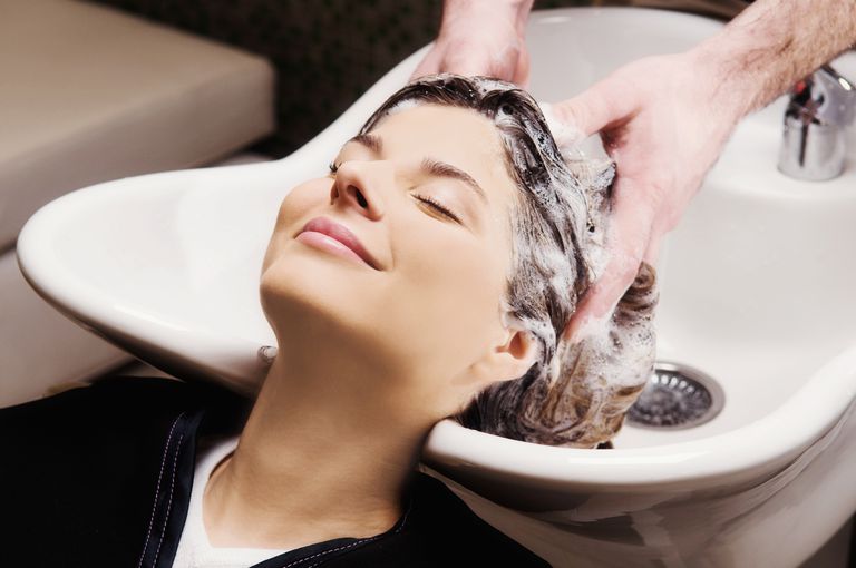 Genç woman getting hair shampooed at salon