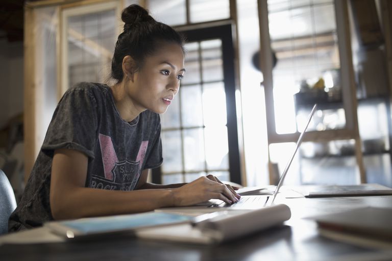 Odaklı young woman working at laptop