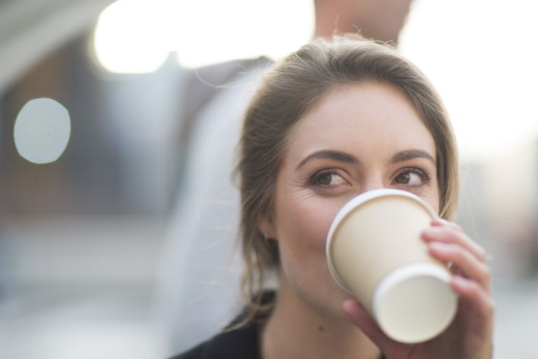 महिला looking away as she sips coffee.