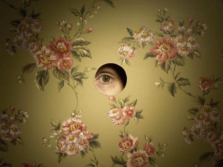 un eye looking through a peep hole in a wall.