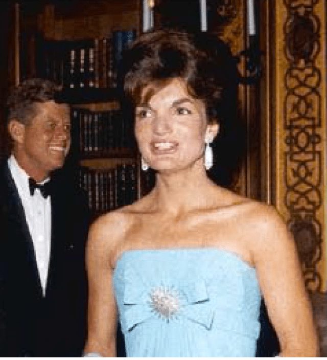 Jackie wears a blue gown with jewelry