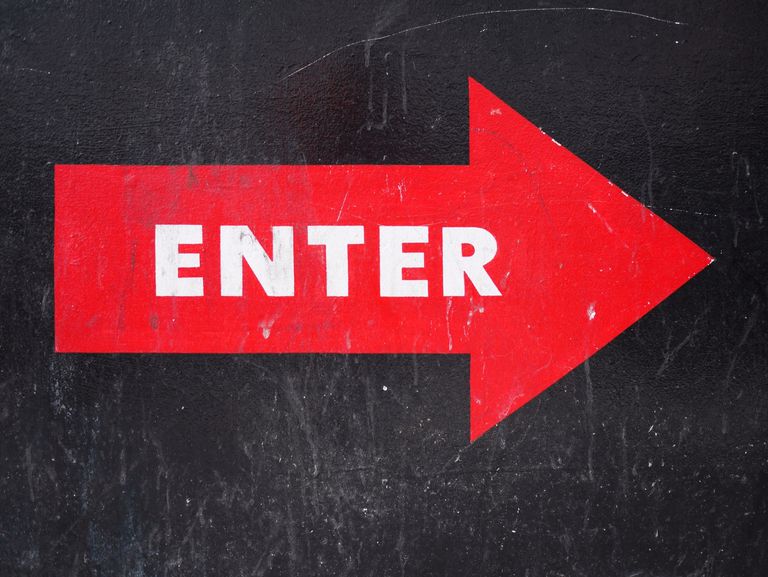 stänga up of an enter sign on a wall, a red arrow with the word enter in white