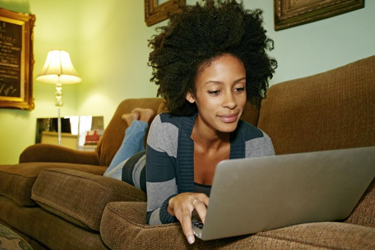 מעורב race woman using laptop on sofa