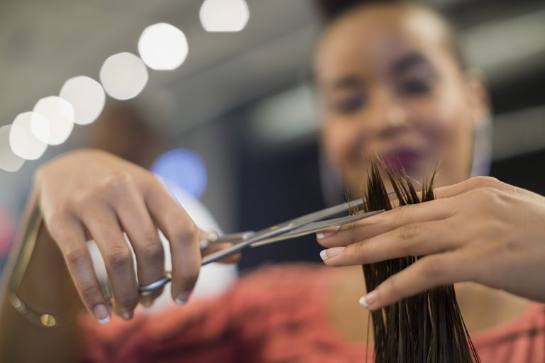 לִסְגוֹר up hairstylist cutting hair in hair salon