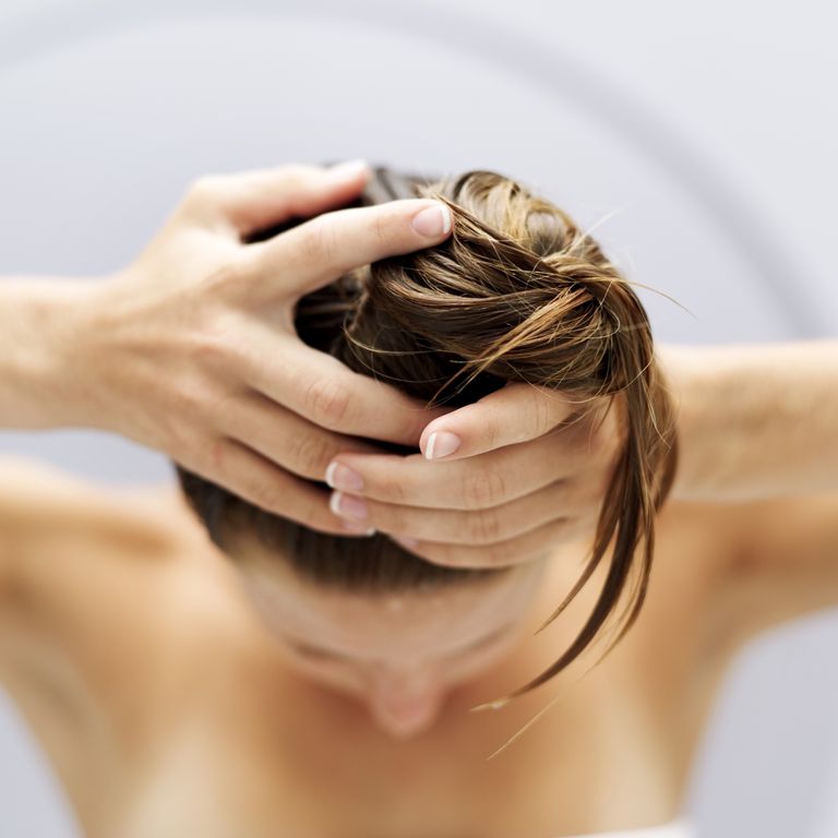 Visoka angle view of a woman piling her hair up into a bun