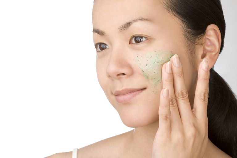 जापानी Woman using facial scrub on her face.