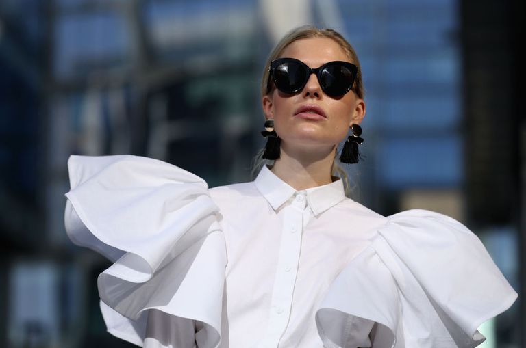 Kadın wearing white blouse and black tassel earrings and black sunglasses