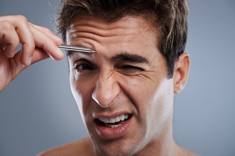 bir man tweezing his eyebrows.