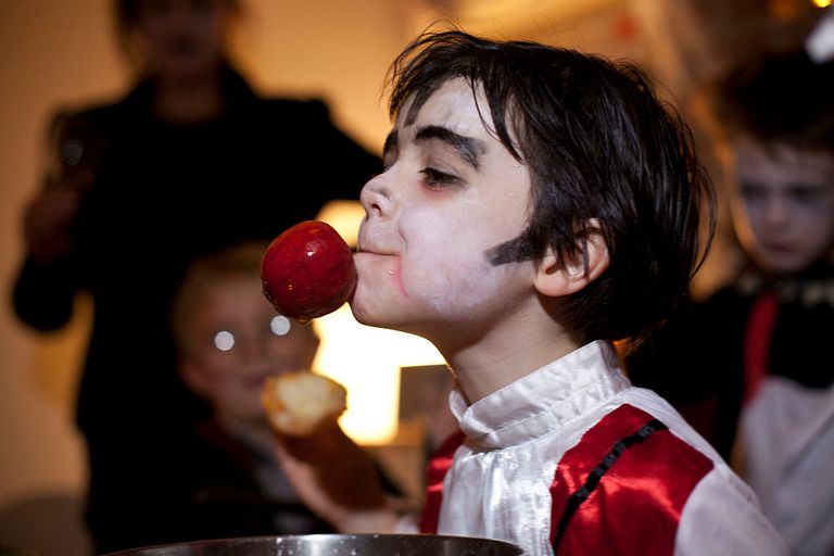 Дете dressed as Dracula bobbing for apples