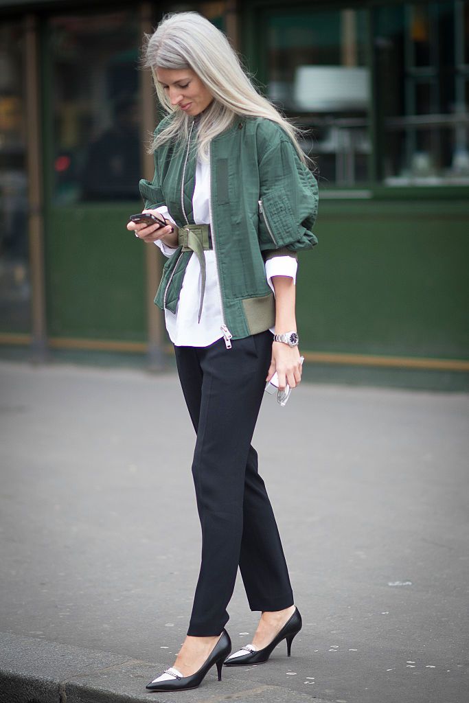 שרה Harris in black jeans and an olive jacket