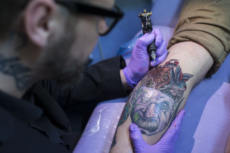 tattooist creates a tattoo featuring an image of Albert Einstein.
